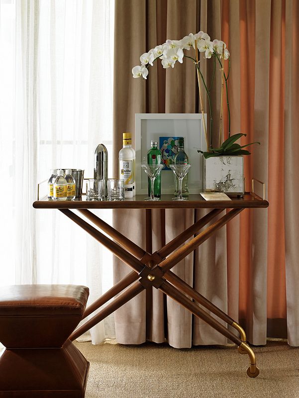 image of bar cart set up with orchid and drinks in front of window with curtains